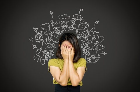 A woman covering her face, surrounded by tangled chalk scribbles