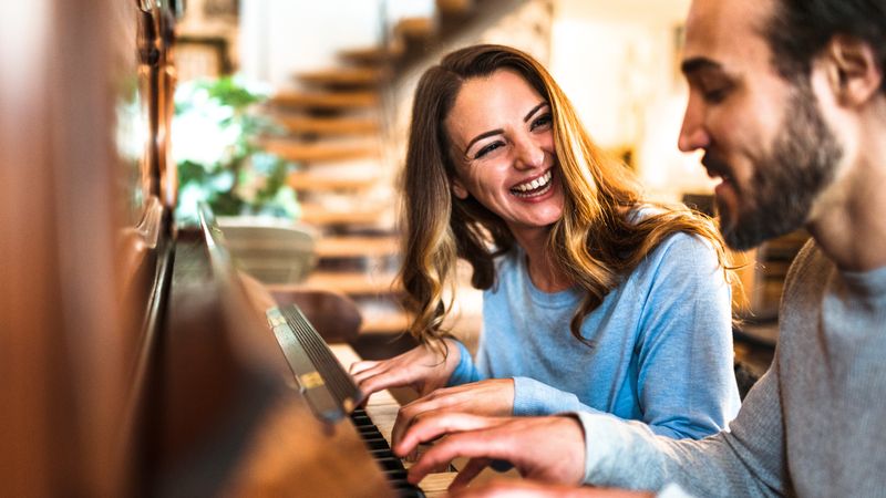 A laughing couple playing the piano together